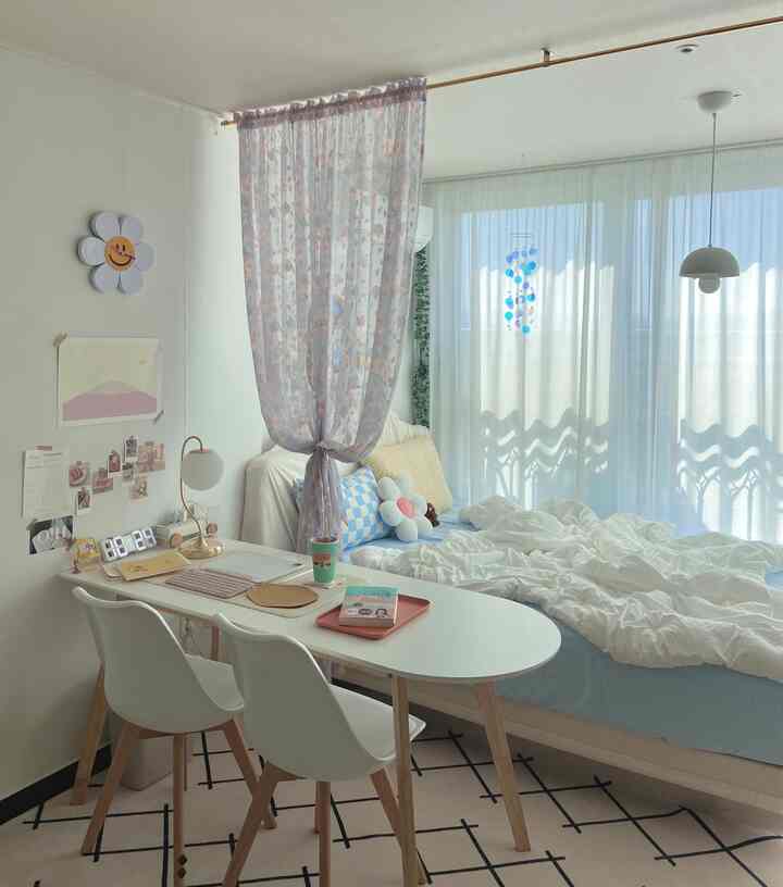 White and light brown toned bedroom featuring bright curtains and a home office table for a cozy atmosphere