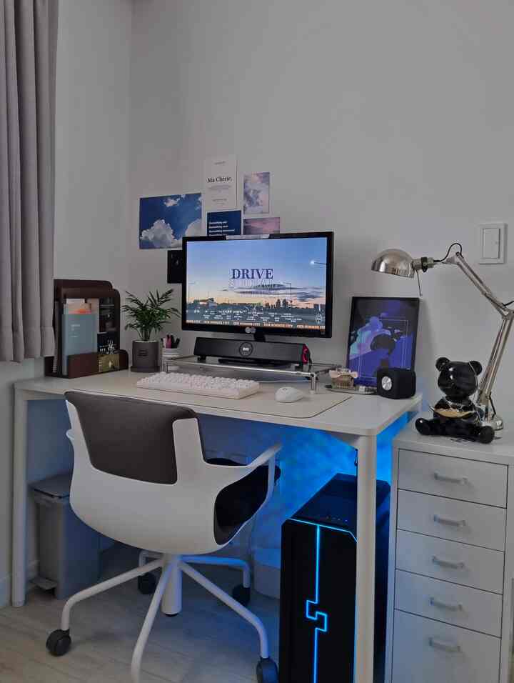 White-toned home office space featuring a computer desk, ergonomic office chair, and a dresser arranged neatly for a modern work environment