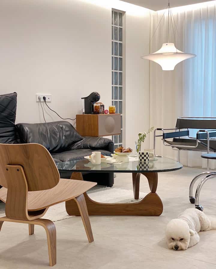 White walls and wood-tone furniture with black leather sofa and armchairs in a natural modern living room