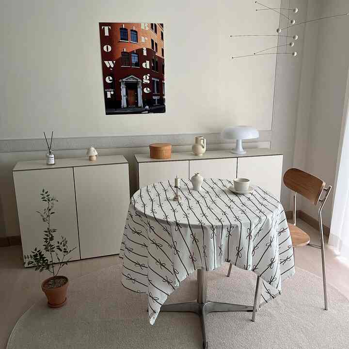 ベージュのナチュラルトーンが広がる6畳の部屋、丸いダイニングテーブルと椅子、壁アートと照明が配置された雰囲気のあるおうちカフェ