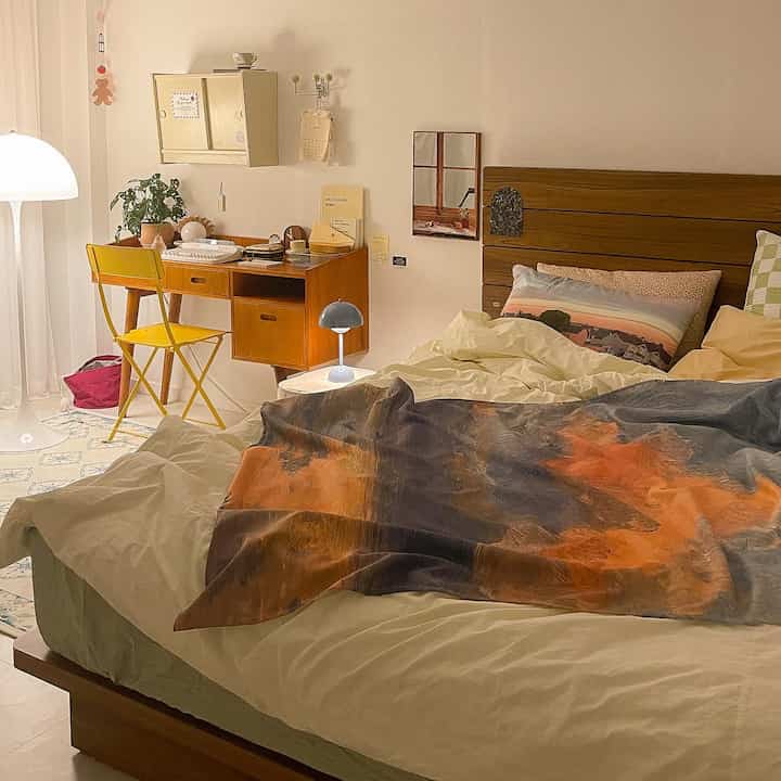 Cozy bedroom in warm beige and brown tones, featuring a wooden bed and desk with natural decor