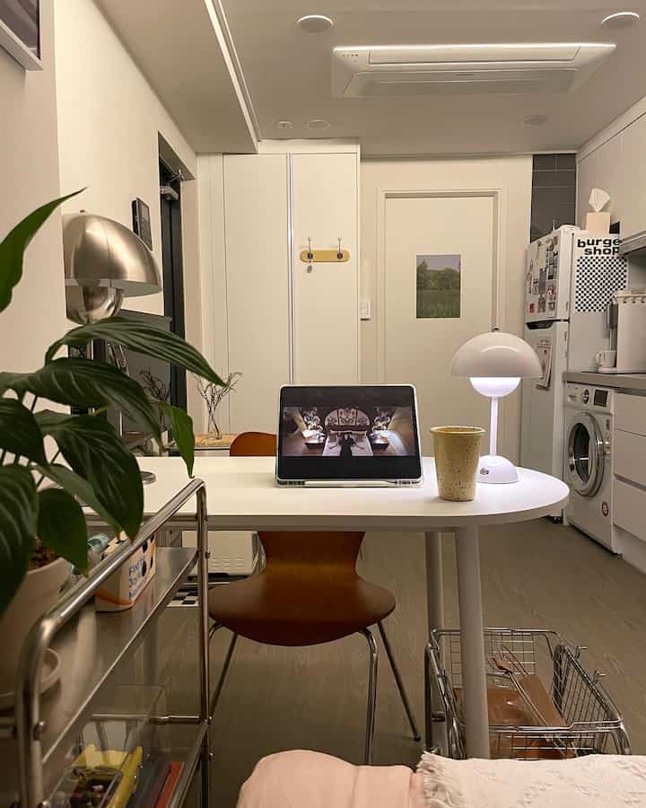 白を基調としたワンルーム、中央のテーブルにiPadとテーブルランプが置かれた、シンプルで落ち着いたホームシネマのある雰囲気のインテリア