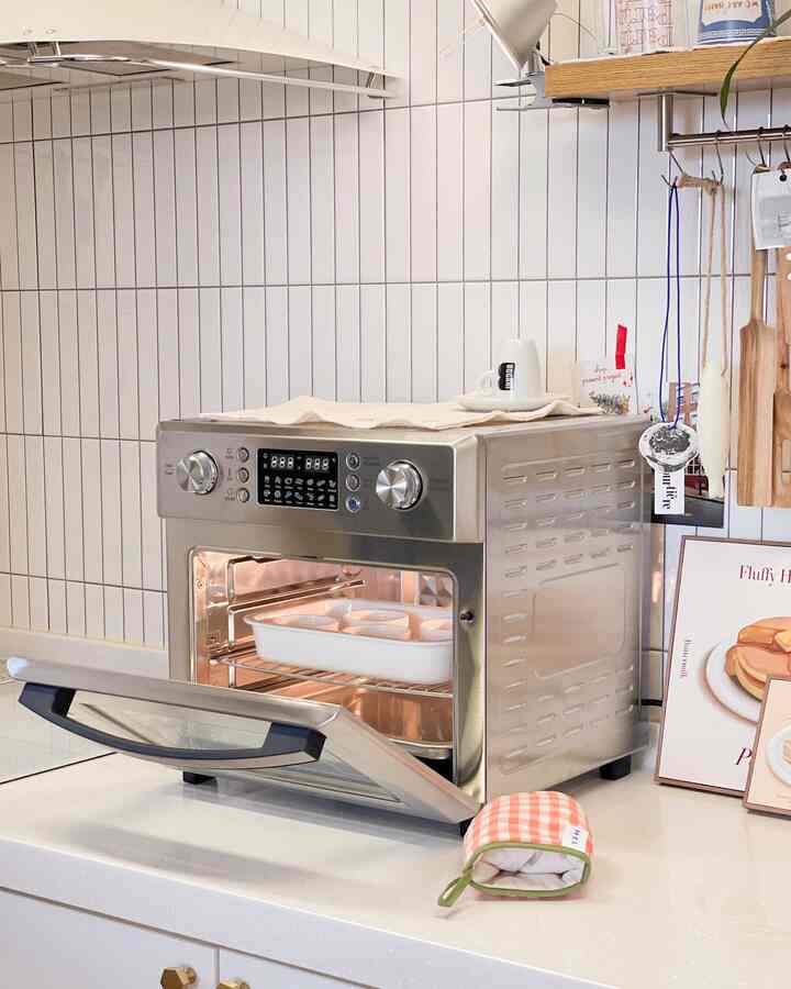 白いタイルの壁とシルバーのステンレス製エアフライヤーオーブンが配置された清潔感のあるキッチン