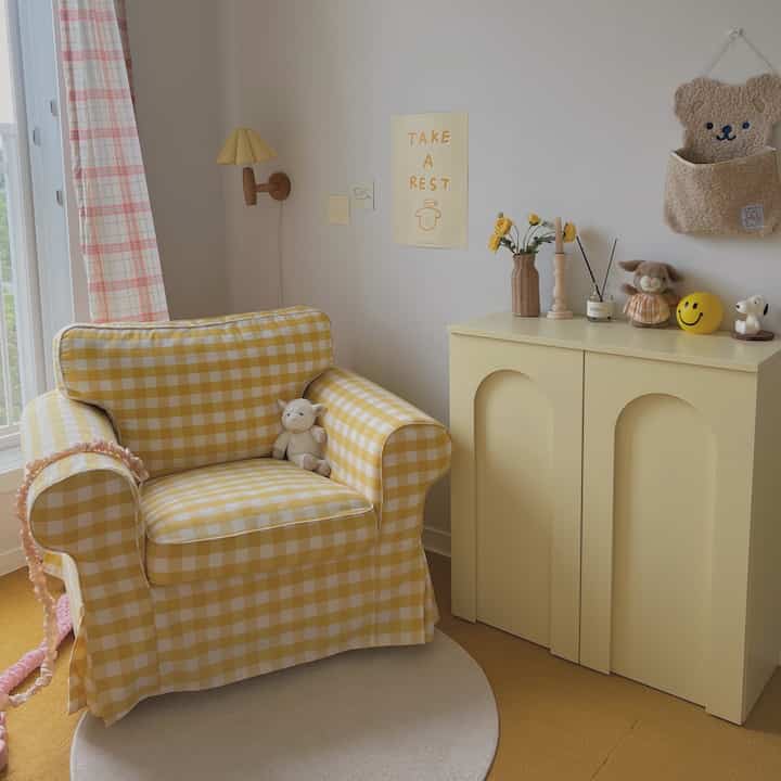 黄色の温かみある子供部屋、黄色のチェック柄のアームチェアとキャビネットが配置された雰囲気のある空間