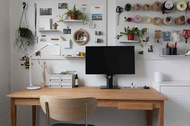 White walls and wood tone desk define a study-style home office featuring organized storage ideas and a clean, systematic setup