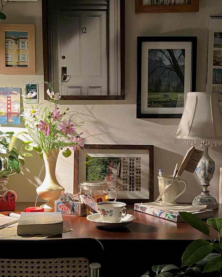 Warm wood tone and natural colors define this home office space featuring a vase of flowers and picture frames creating a cozy mood.