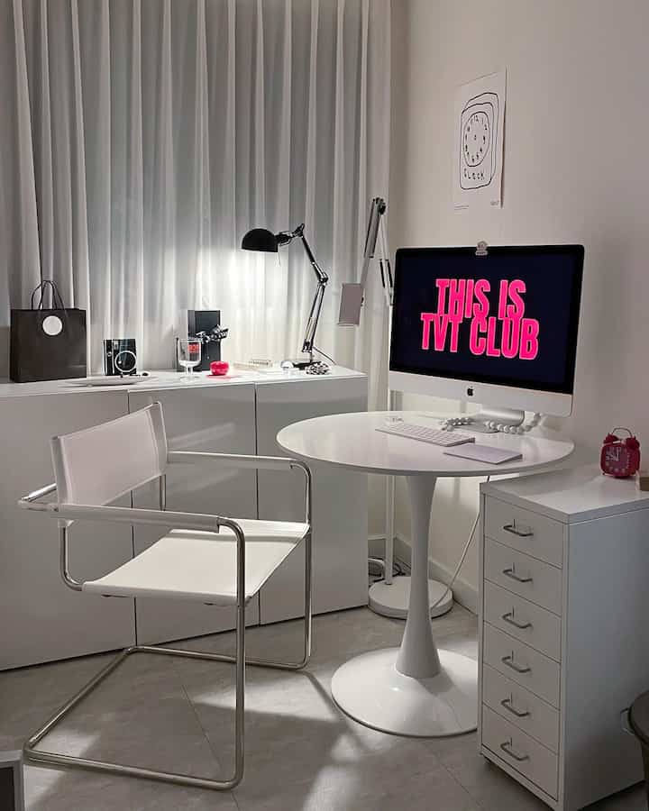 白を基調としたホームオフィス、円形テーブルとチェストが配置されたシンプルでモダンなインテリア