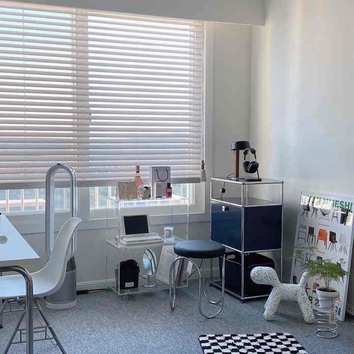 Bright white-toned home office space featuring window blinds and modern furniture with a clean workspace atmosphere