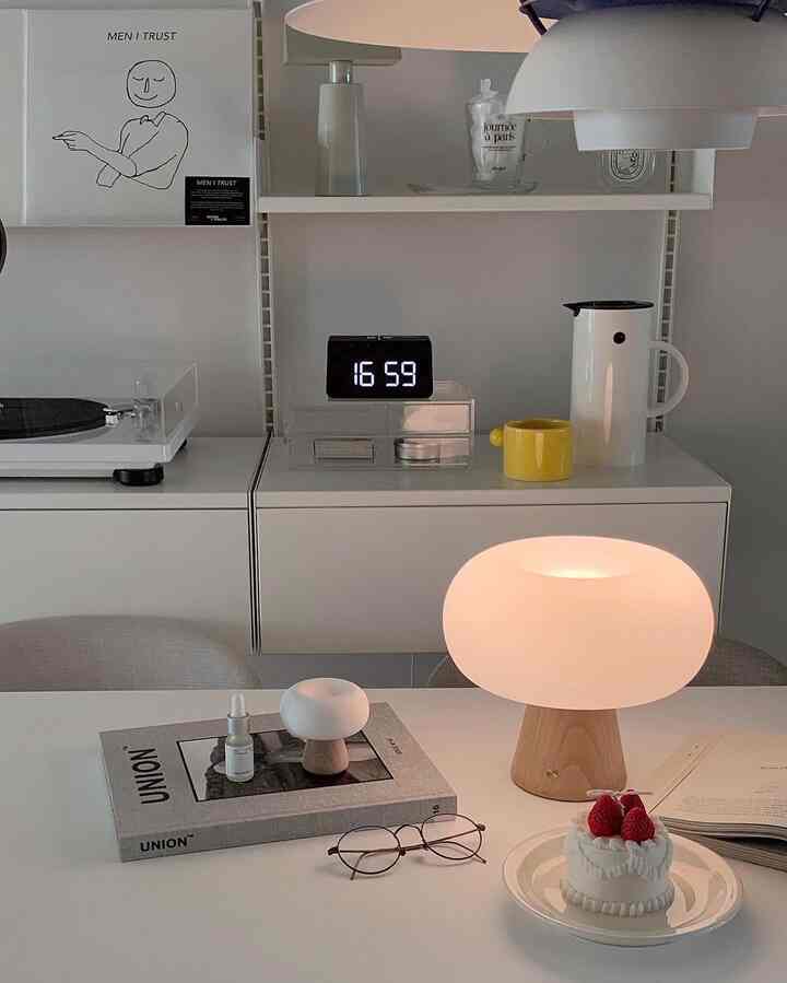 白とベージュのトーンによるミニマルなダイニング空間、テーブルランプとデジタル時計が配置されたすっきりとしたインテリア