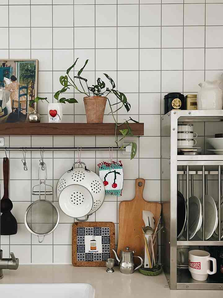 Ivory tiled wall kitchen space featuring wood tone shelf and green plant creating a natural atmosphere