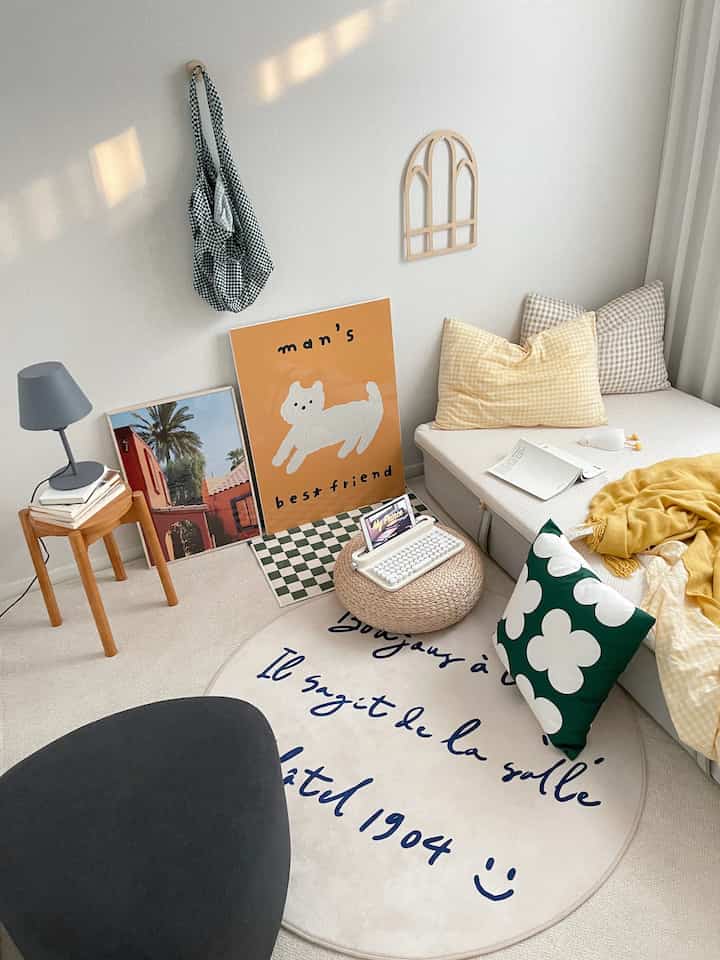 Compact small bedroom with white walls and wood-tone furniture, accented by yellow and vivid green cushions creating a cozy atmosphere