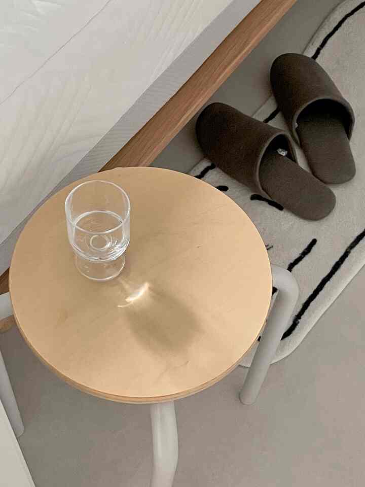 Natural-colored small space featuring a Muji stool and a cat-patterned rug in a simple, cozy atmosphere