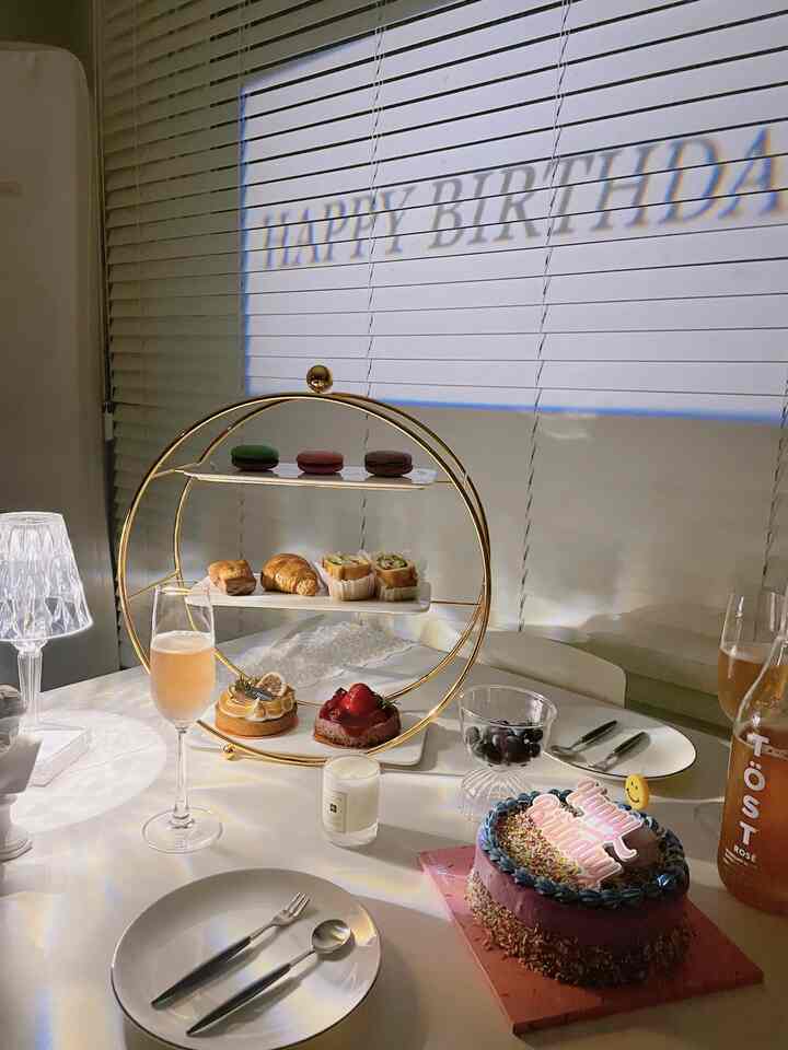 White and gold toned home party table featuring an afternoon tea tray and birthday cake in a cozy setting