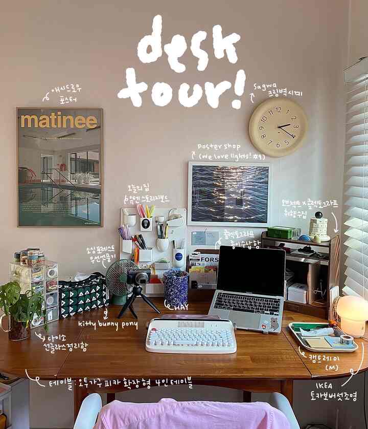 Modern home office with white and brown tones, featuring a large wooden desk, organized stationery, posters and a clock on the wall