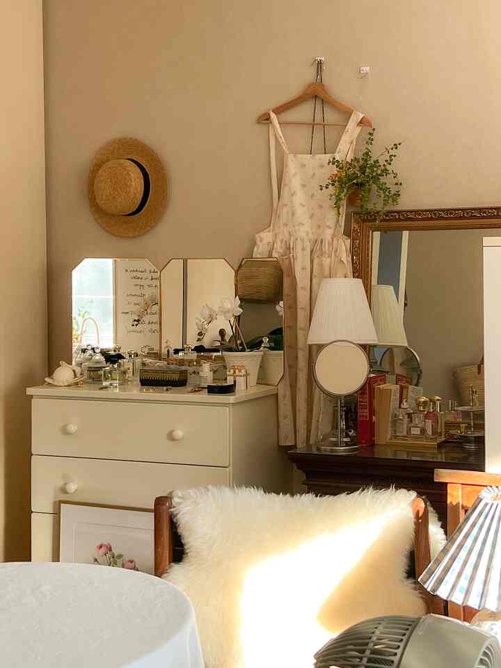 温かみのあるベージュ色の壁とナチュラルな木製家具が配置された寝室、エプロンと鏡が印象的な空間