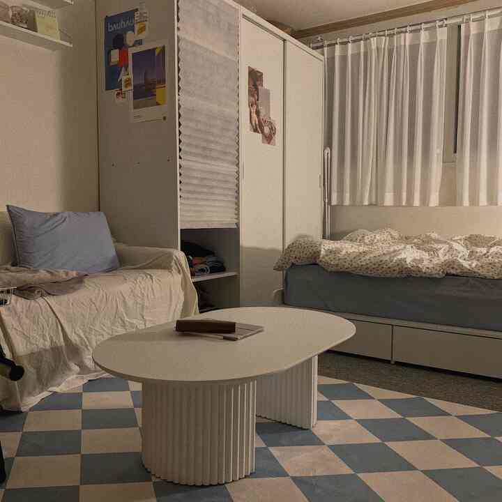 A small bedroom space in white and blue tones featuring a sofa, bed, closet, and coffee table creating a cozy atmosphere