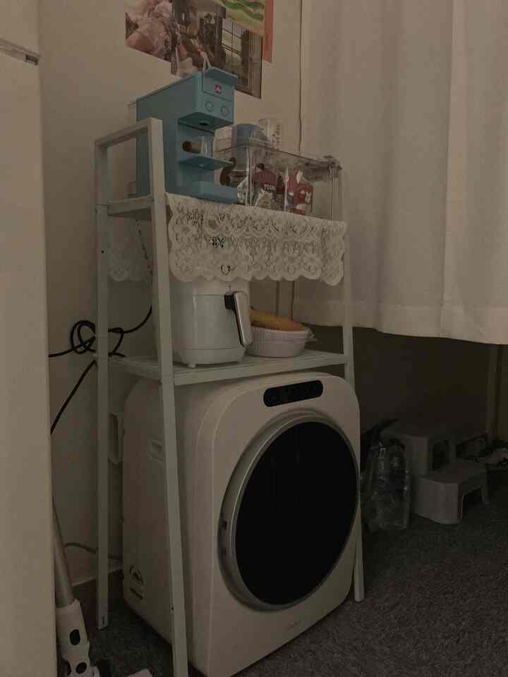 白を基調とした狭い部屋に鉄製収納棚とミニ乾燥機、コーヒーマシンが配置された雰囲気のあるインテリア