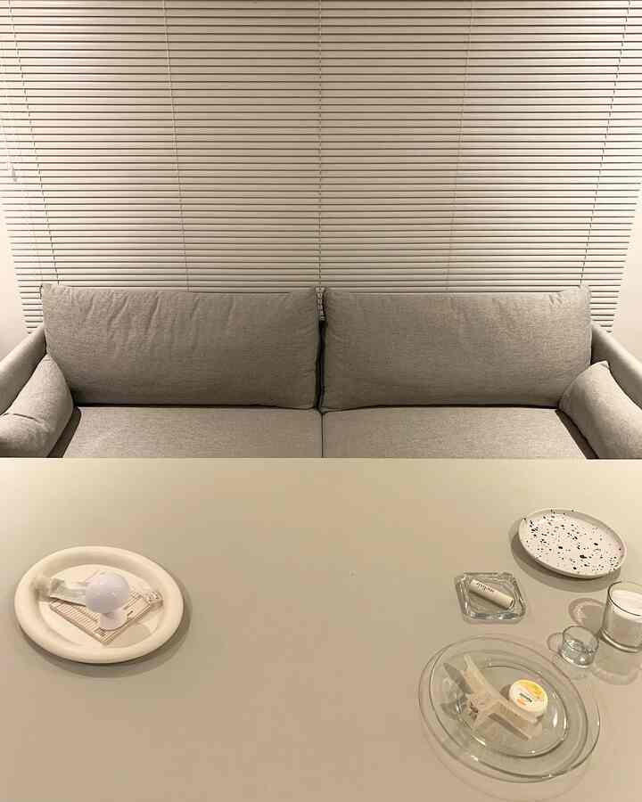 白とグレーのトーンのリビング、グレーのソファと大きなテーブルが配置されたシンプルな空間