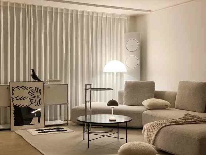 Beige and white toned living room featuring large sofa and floor lamp with cozy modern atmosphere