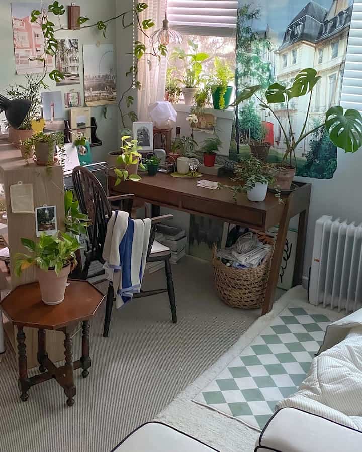 Natural-toned study filled with green plants, featuring a wooden desk and chair in a cozy setup