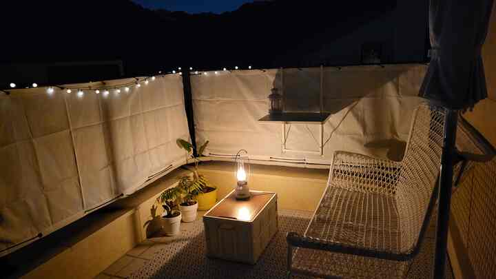 Natural warm-toned terrace with string lights and lantern, creating a cozy outdoor relaxation space