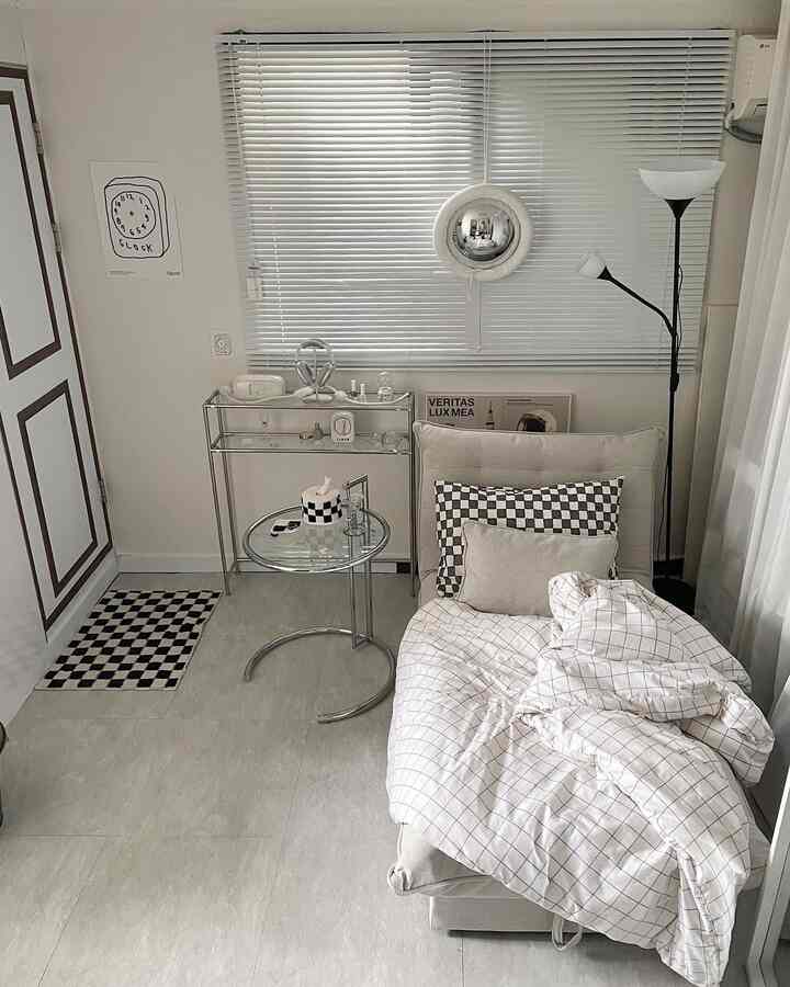 White and gray toned studio apartment living room featuring a mid-century modern sofa bed and side table in a cozy setting