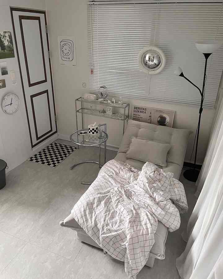 White and gray toned studio apartment featuring a sofa bed and side table in a clean, modern setting