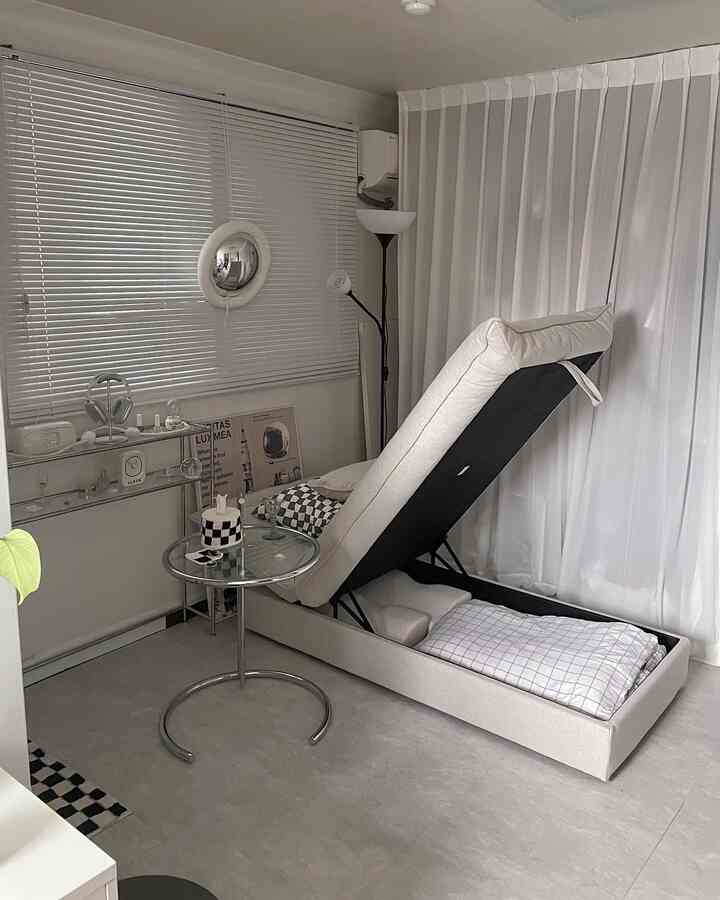 ベージュと白のトーンのコンパクトなリビング、収納機能付きのソファベッドとサイドテーブルが配置されたモダンな空間