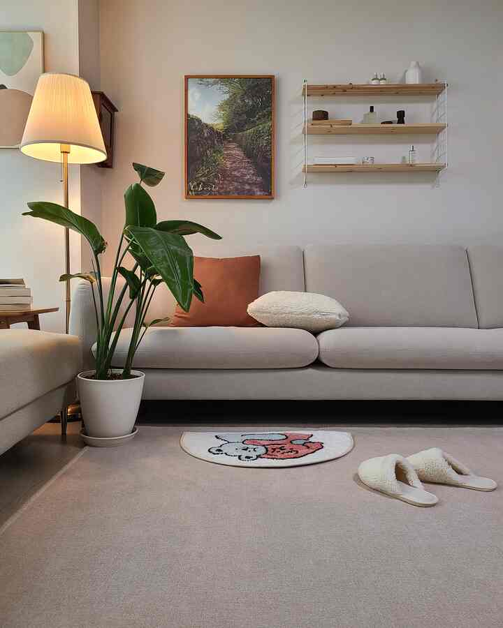 Beige and white toned living room with simple sofa and cushions, a leafy plant, creating a natural atmosphere