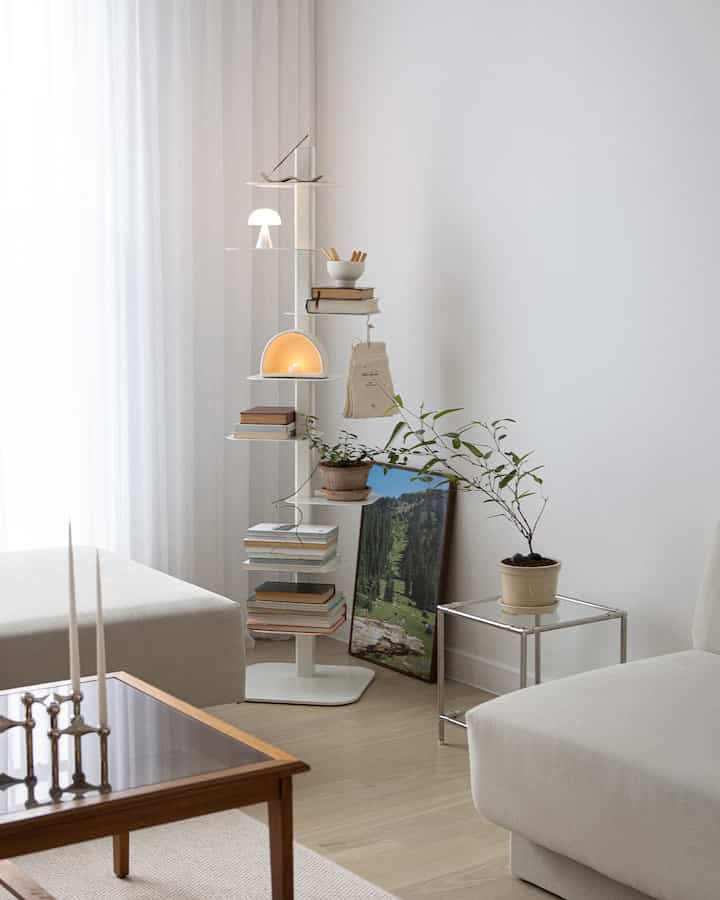 白とナチュラルカラーのリビング、中央に棚と植物が配置されたシンプルで落ち着いたインテリア