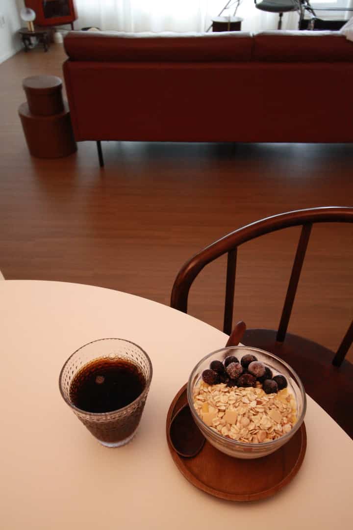 Brown wood tone dining room featuring a round table with a coffee glass and oatmeal bowl, natural and cozy ambiance
