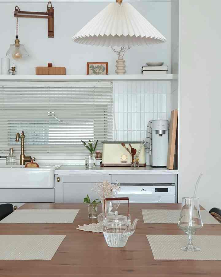White walls and wood tone dining table harmonize in this kitchen space featuring a simple, minimal interior design