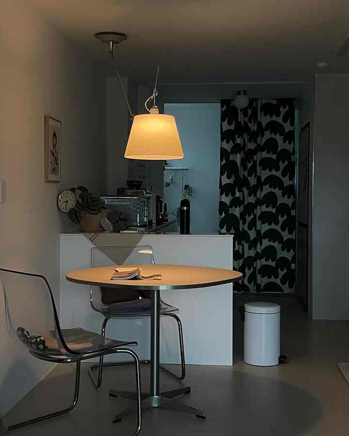 Calm ivory and white toned kitchen dining area featuring transparent chairs and patterned curtains, creating a cozy atmosphere