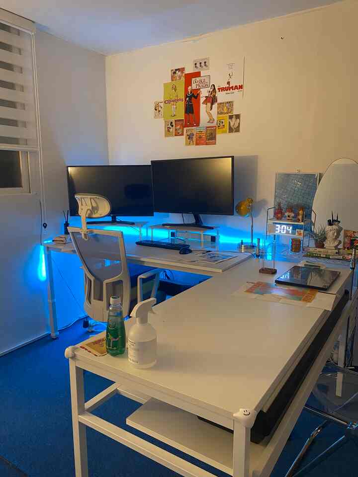 Modern and clean home office space in white and blue tones featuring L-shaped desks, dual monitors, and an office chair