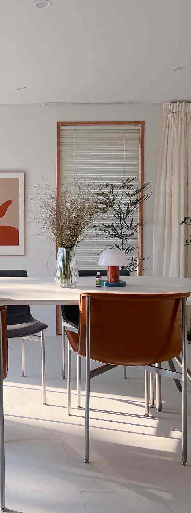 Bright dining room in white and natural tones, simple dining table and chairs with natural light streaming in