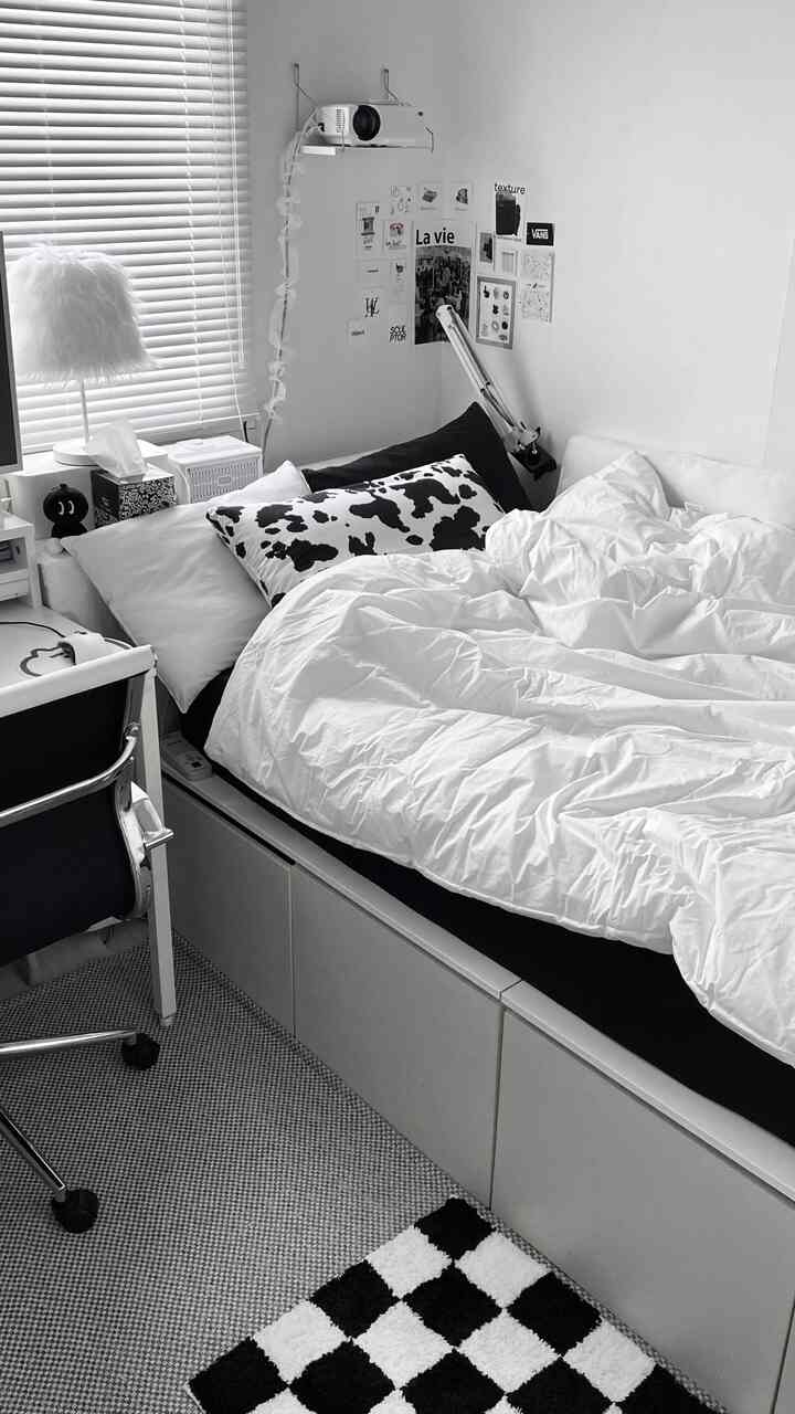 白と黒のトーンの寝室、ベッドとデスク、オフィスチェアがモダンな雰囲気を作り出している印象的な空間