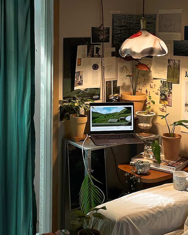 ネイビーカーテンと木製サイドテーブル、植物が配置されたワンルームのホームオフィス空間