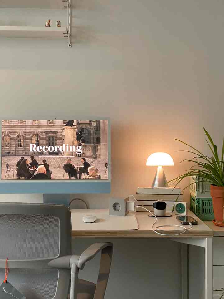 A natural-toned home office featuring beige walls and a wooden desk, with an iMac, table lamp, and plant creating a cozy study atmosphere
