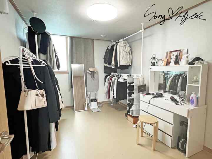 白とベージュの色調が特徴的な狭いドレッシングルーム、複数の洋服掛けと化粧台が配置された実用的なインテリア