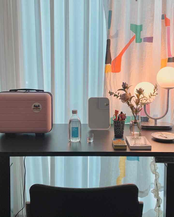 Soft pastel tones and black hues blend in a home office featuring a tidy desk with decorative lighting and accessories