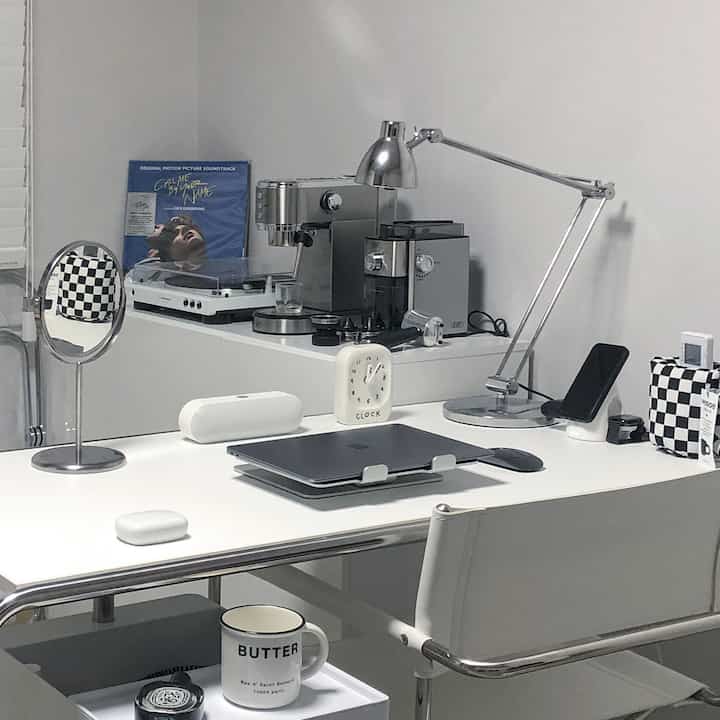 Modern and minimal studio workspace in white and silver tones, featuring a desk, office chair, and home cafe equipment