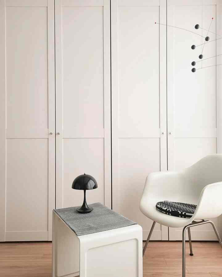 A bright white and natural wood tone modern minimal space, featuring a white armchair and a small side table in a tidy living area