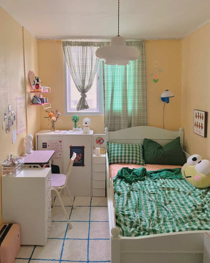 淡い黄色の壁と白い家具、緑のギンガムチェックの寝具が配置された子供部屋の雰囲気のあるインテリア