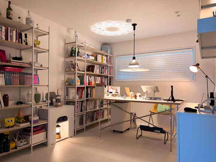 White-toned home office space featuring bookshelves and desk with a clean, modern atmosphere