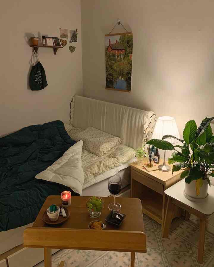 Natural color bedroom featuring a bed with nightstand, table lamp, floor lamp, and a plant, creating a cozy atmosphere