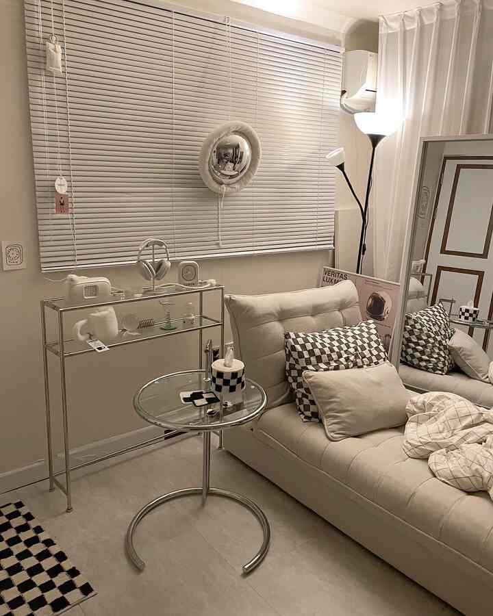 ベージュと白の色調のリビング、ソファベッドと金属製のサイドおよびコンソールテーブルが配置されたモダンでミニマルな印象的な空間