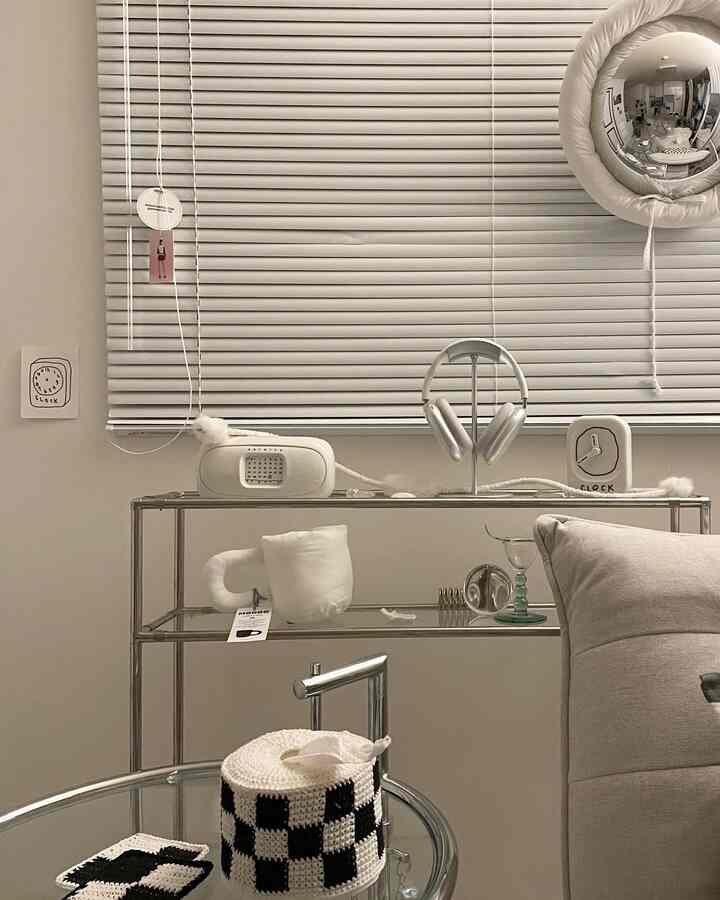 Natural tone living room with beige sofa bed, stainless steel console table, and white aluminum blinds creating a modern atmosphere