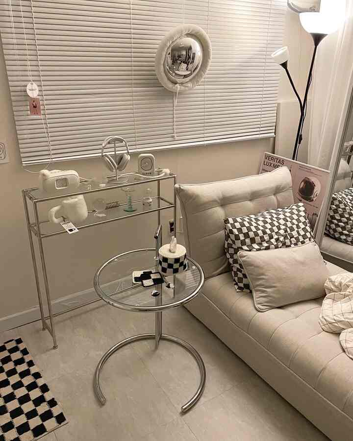 Beige and white toned living room featuring a sofa bed, console table, and aluminum blinds in a simple modern setting