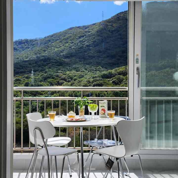Bright white-toned veranda featuring a round dining table and white chairs bathed in natural light