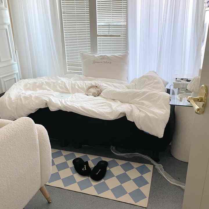 A white and black toned bedroom featuring a sofa bed and white curtains, creating a cozy atmosphere